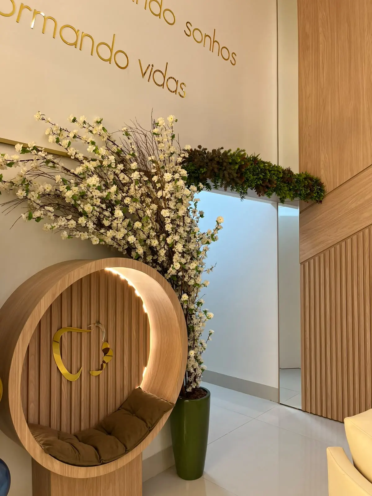 Detalhe da sala de espera: moldura redonda com flores e a frase da parede